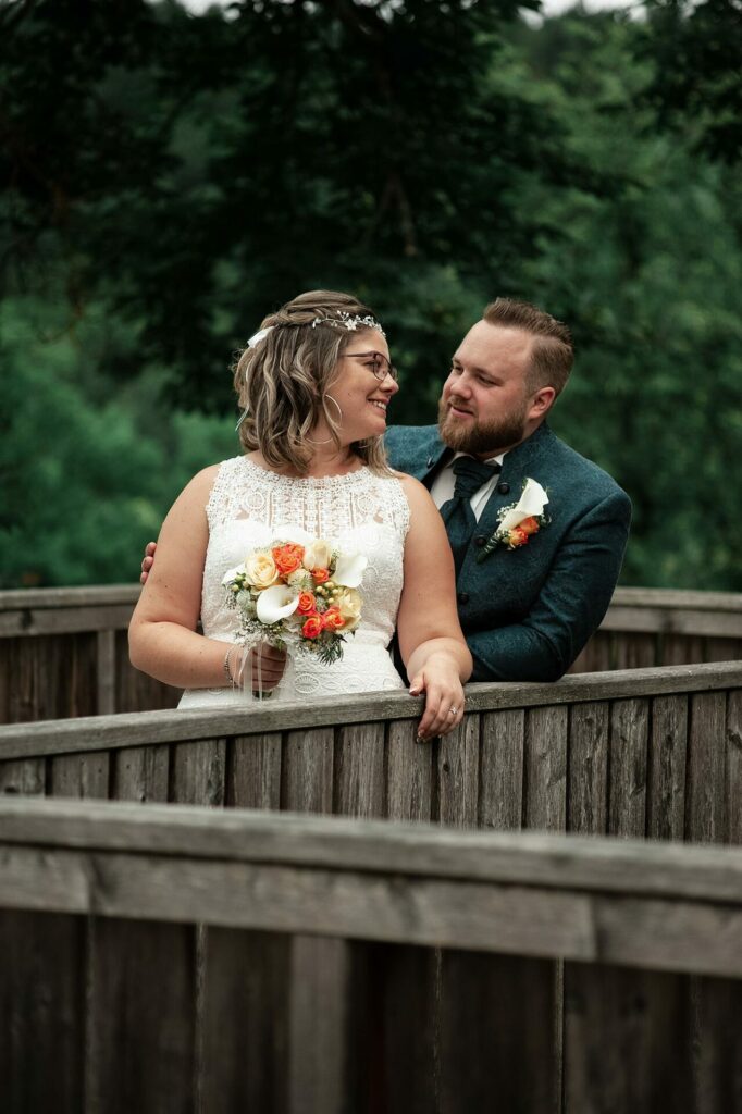 Emotionales Bild vom Shooting mit dem Hochzeitspaar, das auf einer Brücke steht. und sich anlächelt.