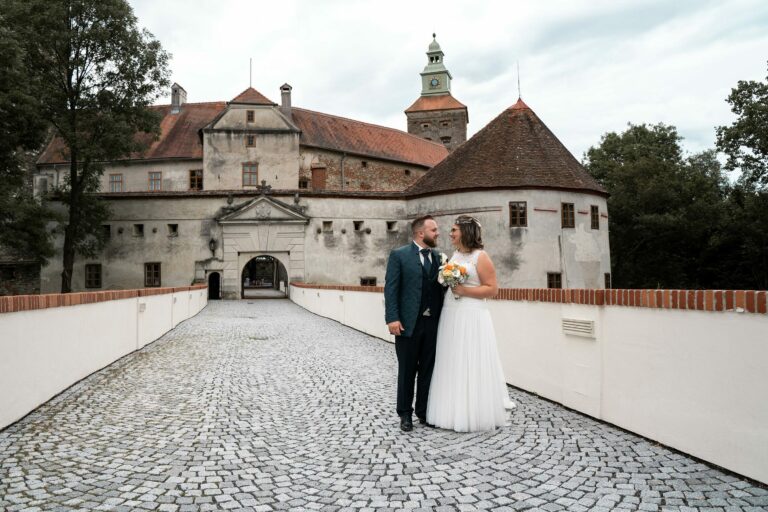 Hochzeitspaar, das vor der Burg Schlaining steht und sich ansieht.