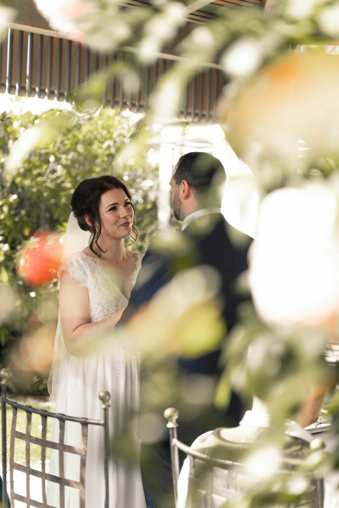 Romantisches Foto aus der Hochzeitsreportage vom Paar, durch Blumen fotografiert.