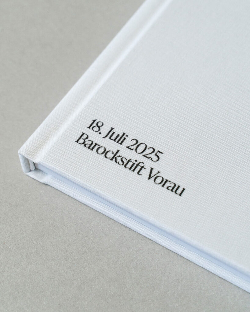 Deteilansicht des Hochzeitsbildbands mit weißem Leineneinband und schwarzer, aufgedruckter Schrift